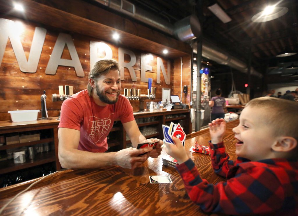 Adam Keck plays Uno with his nephew Henry Keck, at the bar of his brewery.