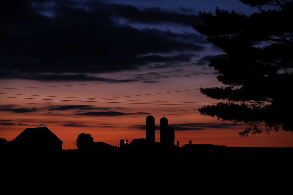 Sun sets behind farms silos.