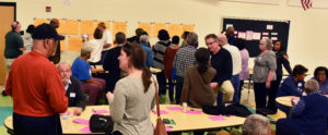 A group of people gather in front of sticky notes places on a wall.