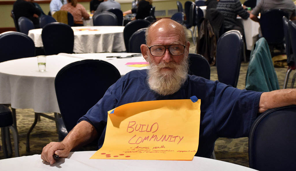 A man with a sticky note that says "build community"